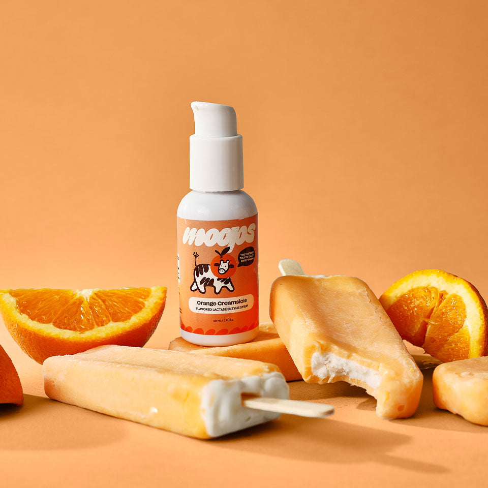Orange Creamsicle bottle next to popsicles and orange slices